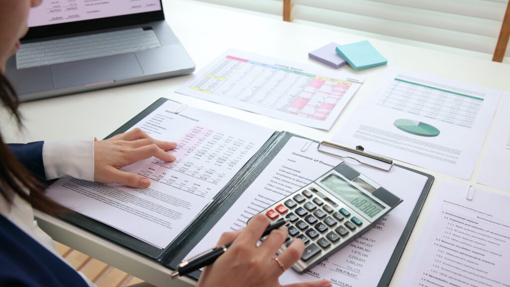 A business person from Shartru Wealth works on a laptop with an overlay of financial icons.