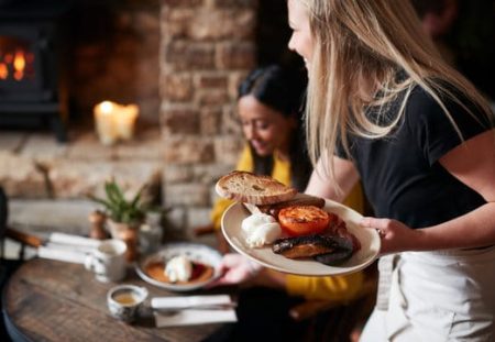 Shartru Wealth Management highlights hospitality worker crisis with waitress serving food in restaurant.
