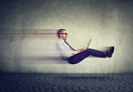 A business person from Shartru Wealth works on a laptop while being pulled along by an unseen force.