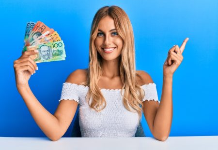 A smiling Shartru Wealth client holds a fan of Australian money.