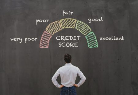 Shartru Wealth image of man looking at chalkboard with credit score scale from poor to excellent.