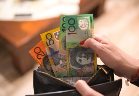 Shartru Wealth photo of a person holding Australian $20, $50 and $100 banknotes in a wallet.