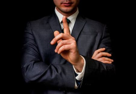 Shartru Wealth Management professional in suit holding finger up, symbolising untold financial advice.