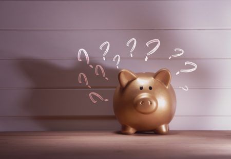 Shartru Wealth golden piggy bank with question marks symbolizing financial uncertainty and smart money saving decisions.