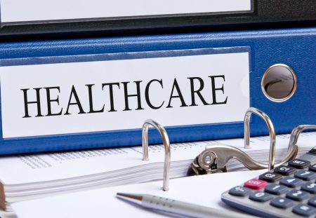 A blue binder from Shartru Wealth is labeled with the word "HEALTHCARE."