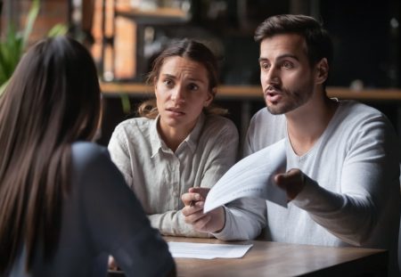 Worried couple reviewing documents with advisor, highlighting Shartru Wealth tips to avoid bad property deals