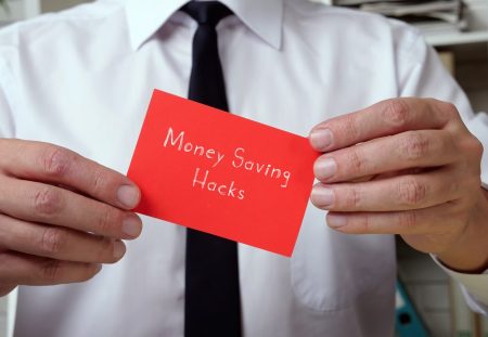 Shartru Wealth image of businessman holding red card with money saving hacks written on it.