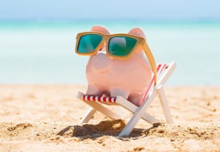 Shartru Wealth Management piggy bank in sunglasses relaxing on beach chair, symbolising retirement savings.