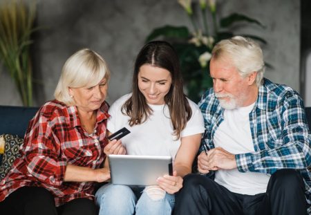 Shartru Wealth image of young woman with parents using tablet and credit card together at home.