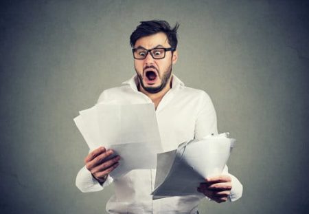 Shocked man holding unexpected bills highlights expense control tips shared by Shartru Wealth Management.