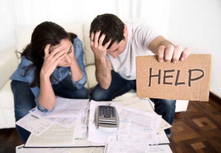A man and a woman from Shartru Wealth look distressed while holding a cardboard sign that says "HELP."