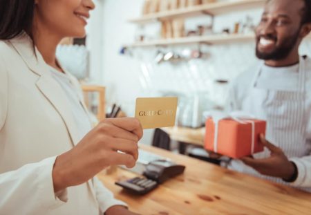 Shartru Wealth customer paying with a gold gift card at a shop counter.