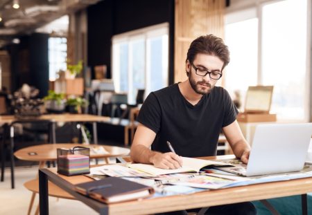 A photo from Shartru Wealth shows a person looking at a laptop and a pile of books.