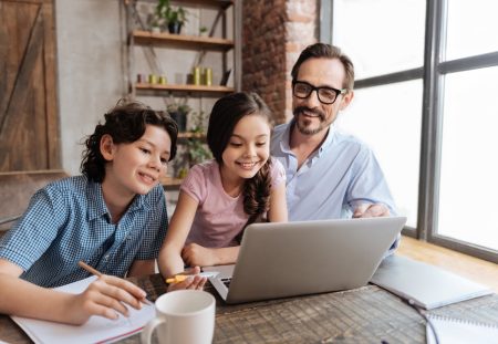 Shartru Wealth photo of father and two children smiling while learning together on a laptop.