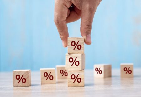 Shartru Wealth image of hand stacking wooden blocks with percentage symbols representing interest rates.