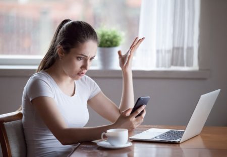 A Shartru Wealth photo shows a confused person looking at a phone and a laptop.