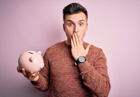 Shartru Wealth highlights biggest money mistakes with shocked man holding piggy bank.