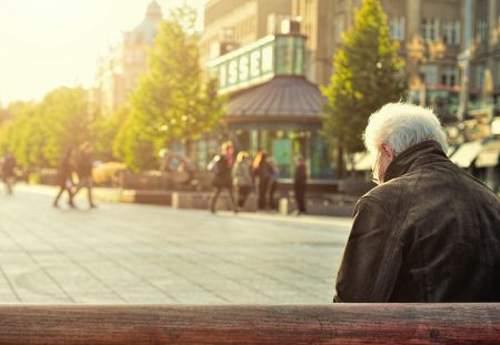 Older man sitting on a bench in sunlight representing retirement planning with Shartru Wealth.