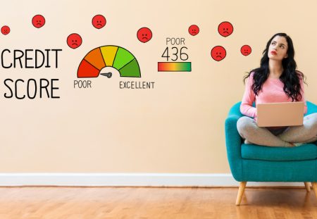 Woman with laptop sitting near credit score graphic showing poor rating, Shartru Wealth credit blog.