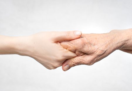 A close-up from Shartru Wealth shows a young person's hand holding an older person's hand.