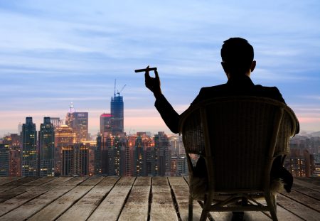 A business person from Shartru Wealth works on a laptop with a cityscape in the background.