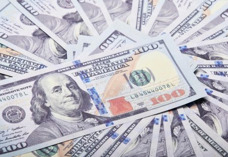 Shartru Wealth image showing multiple US one-hundred dollar bills spread out.