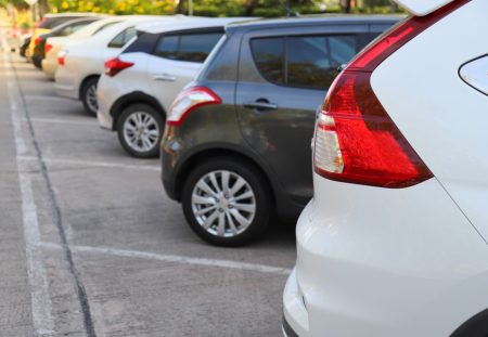 Row of parked cars in outdoor lot, Shartru Wealth explains how to claim car expenses on tax.
