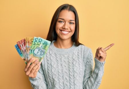 Smiling woman holding Australian dollar notes symbolising wealth management and smart money strategies.