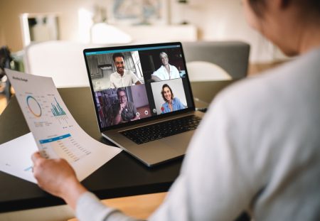 Person reviews budget chart during video conference on laptop, Shartru Wealth discusses remote work challenges.