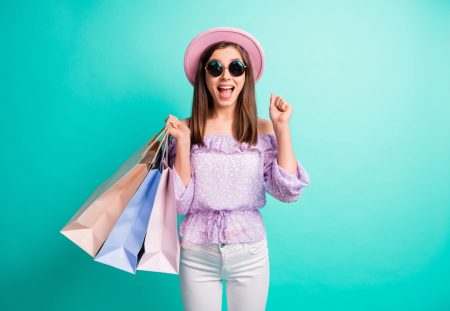 Excited young woman holding shopping bags, showing Shartru Wealth’s old-school saving hack for smart shoppers.