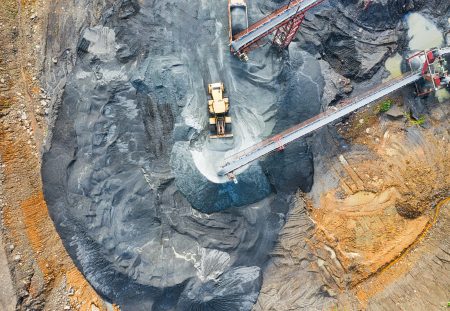 Shartru Wealth aerial view of mining site with heavy machinery and conveyor belts.