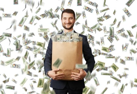 A business person from Shartru Wealth is surrounded by money flying in the air and holds a bag full of money.